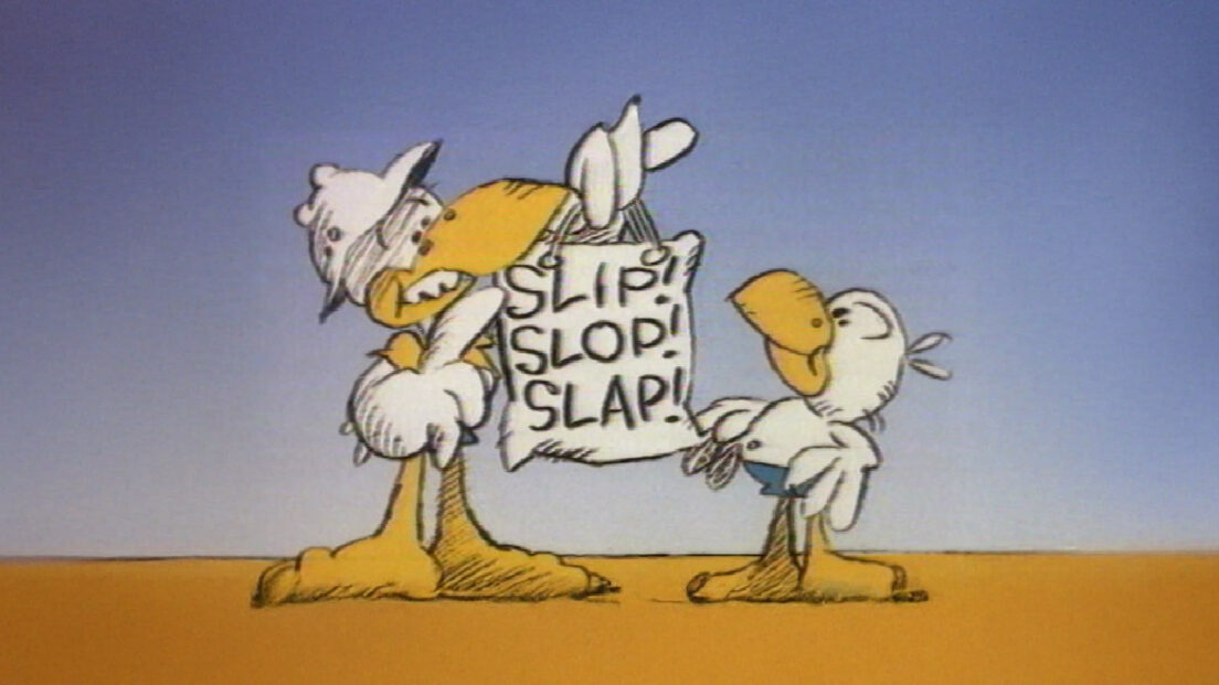 Slip Slop Slap still image from the Australian sun safety campaign showing two cartoon seagulls, one taller seagull leaning in with an arm around a hanging sign that reads Slip Slop Slap, and a smaller seagull standing to the right, with a sandy ground and blue sky behind them